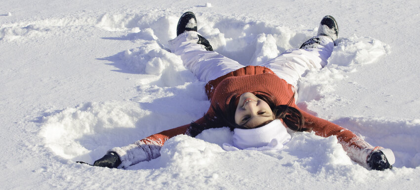 Mädchen liegt lachend im Schnee