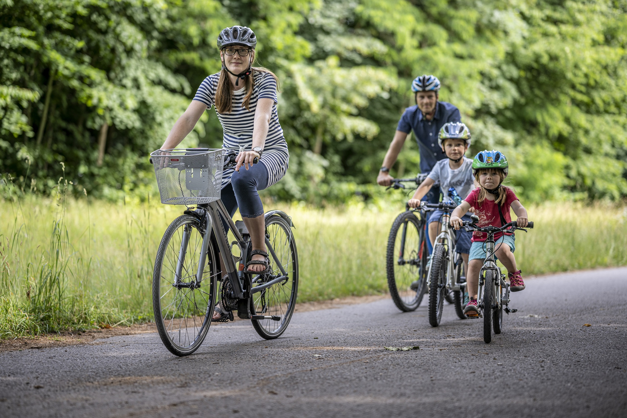 Eine Familie bei einer Radtour im Sommer durch den Stadtpark